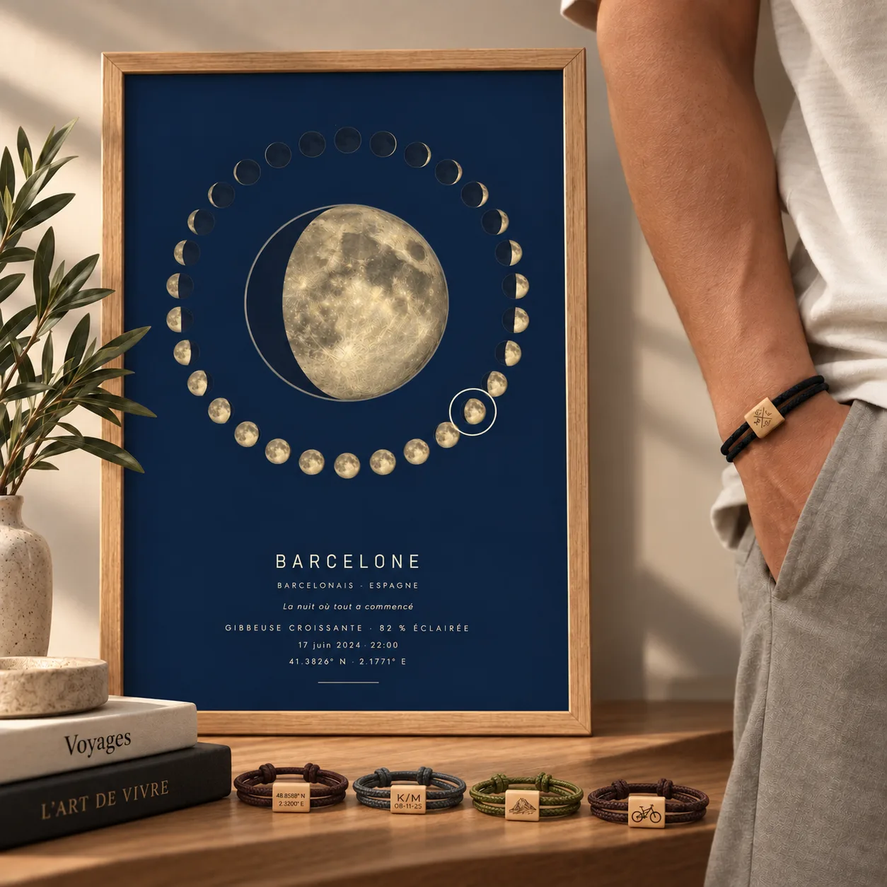 Affiche phase de lune encadrée, quatre bracelets gravés posés devant et un cinquième porté au poignet