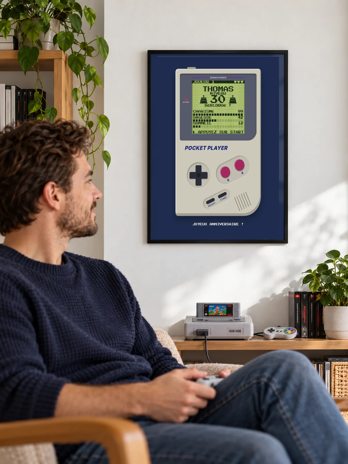 Dans un salon, l’affiche d’anniversaire en console rétro de Thomas est accrochée au mur dans un cadre noir fin près de un homme.