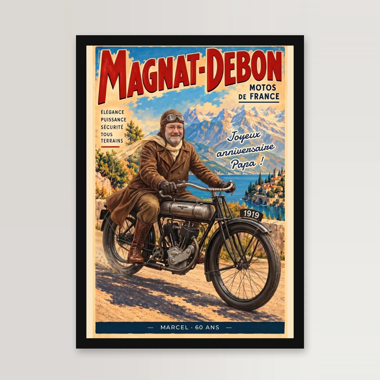 Affiche de moto ancienne dans un cadre noir sur un mur clair : titre MAGNAT-DEBON en capitales rouges, un motard à lunettes et barbe grise, casque de cuir et grand manteau brun, sur une moto de 1919 devant des montagnes et un lac, phrase « Joyeux anniversaire Papa ! » et bandeau bleu « MARCEL · 60 ANS »