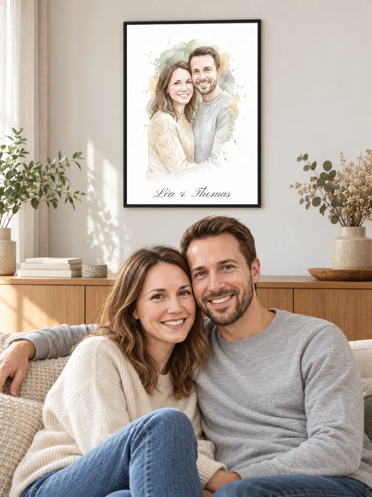 Un couple est assis dans un salon lumineux sous son portrait à l’aquarelle encadré de noir