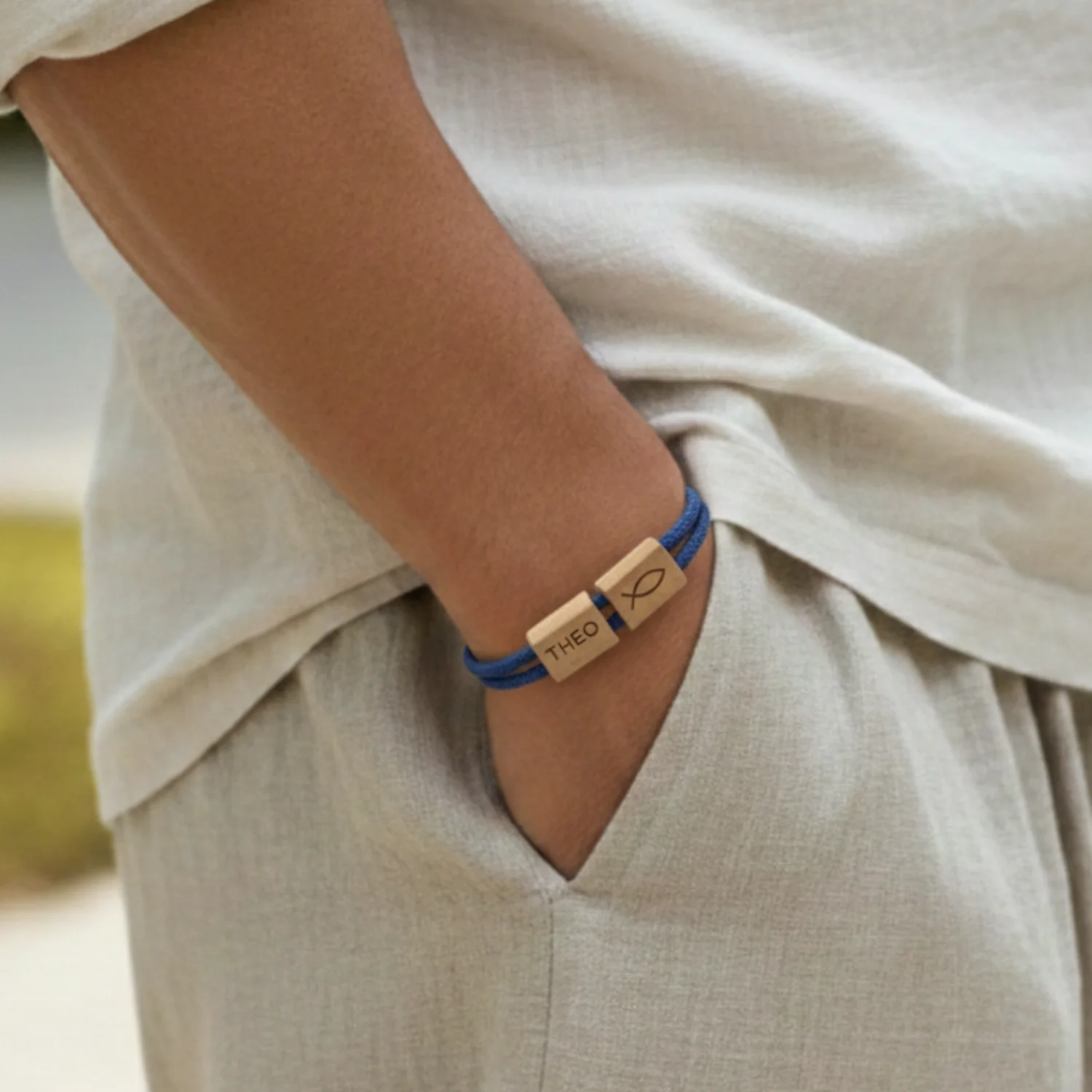 Bracelet bleu à deux passants gravés porté au poignet d'un enfant, en extérieur