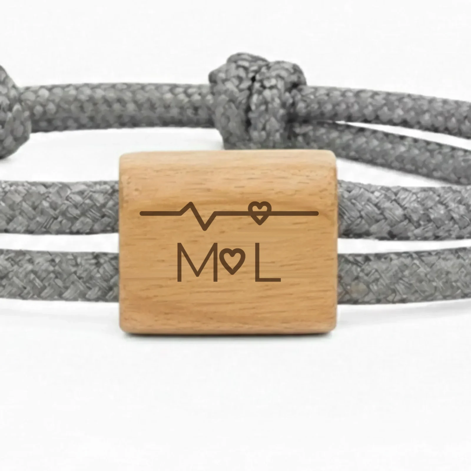 Photographie du bracelet Battement de cœur : gros plan de la pièce en bois de cerisier, gravée d’un tracé de battement de cœur et de deux initiales.