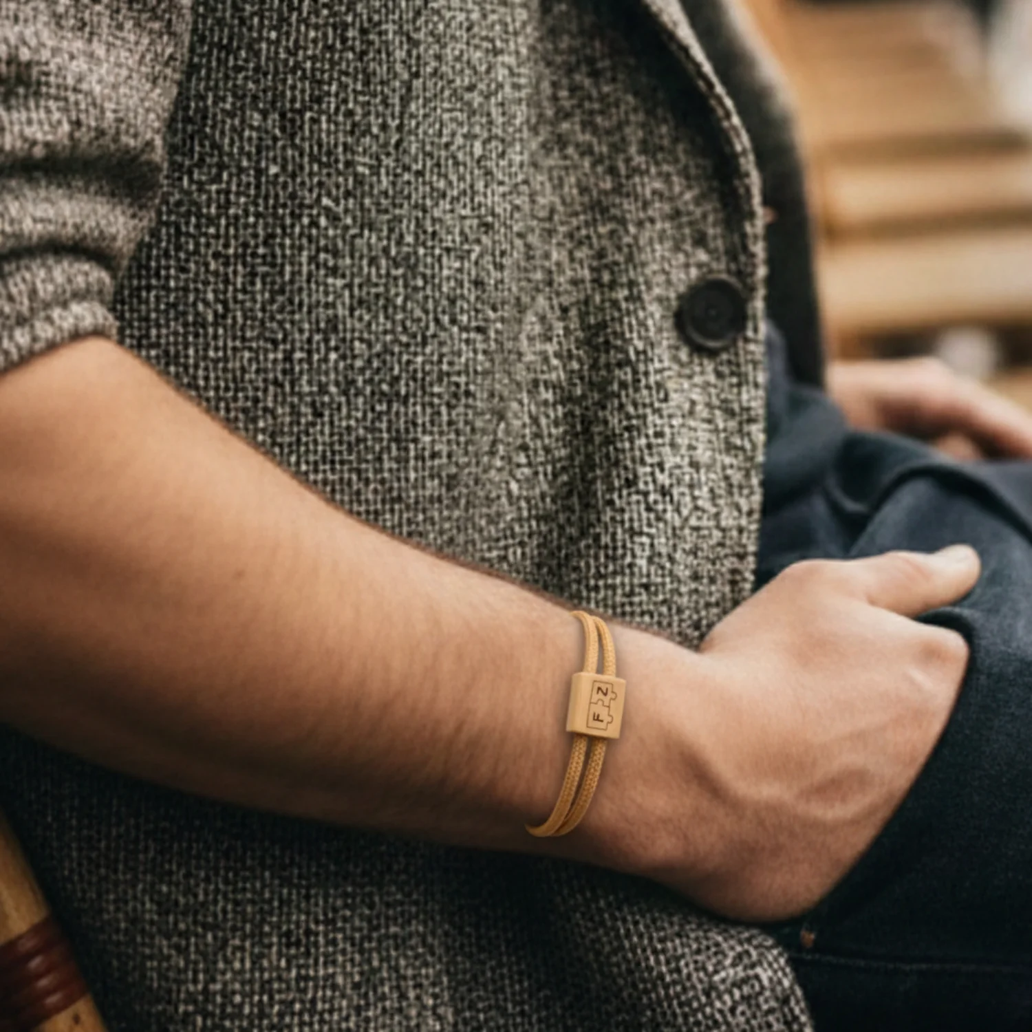 Bracelet caramel porté au poignet, sous la manche d'une veste en tweed