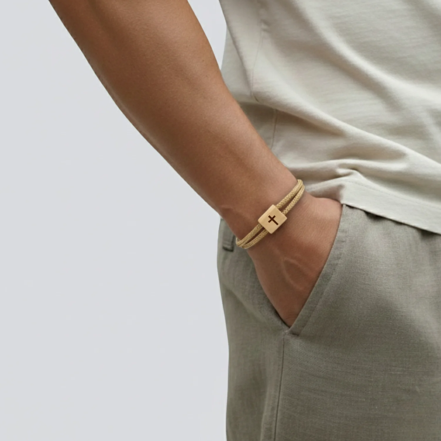 Bracelet porté au poignet d'un homme, main dans la poche d'un pantalon clair