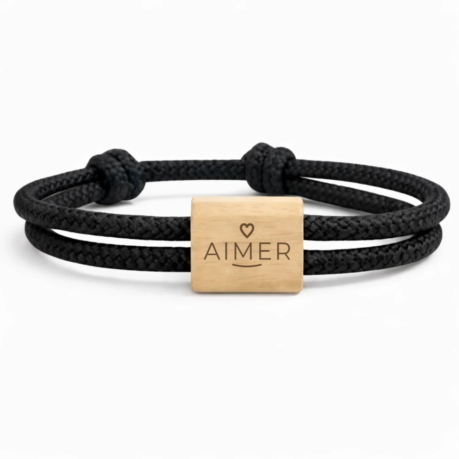 Photographie du bracelet Mot d’intention, cordon noir : cordon marin double à nœuds coulissants et une plaque en bois de cerisier, gravée d’une étoile et d’un mot en écriture manuscrite.
