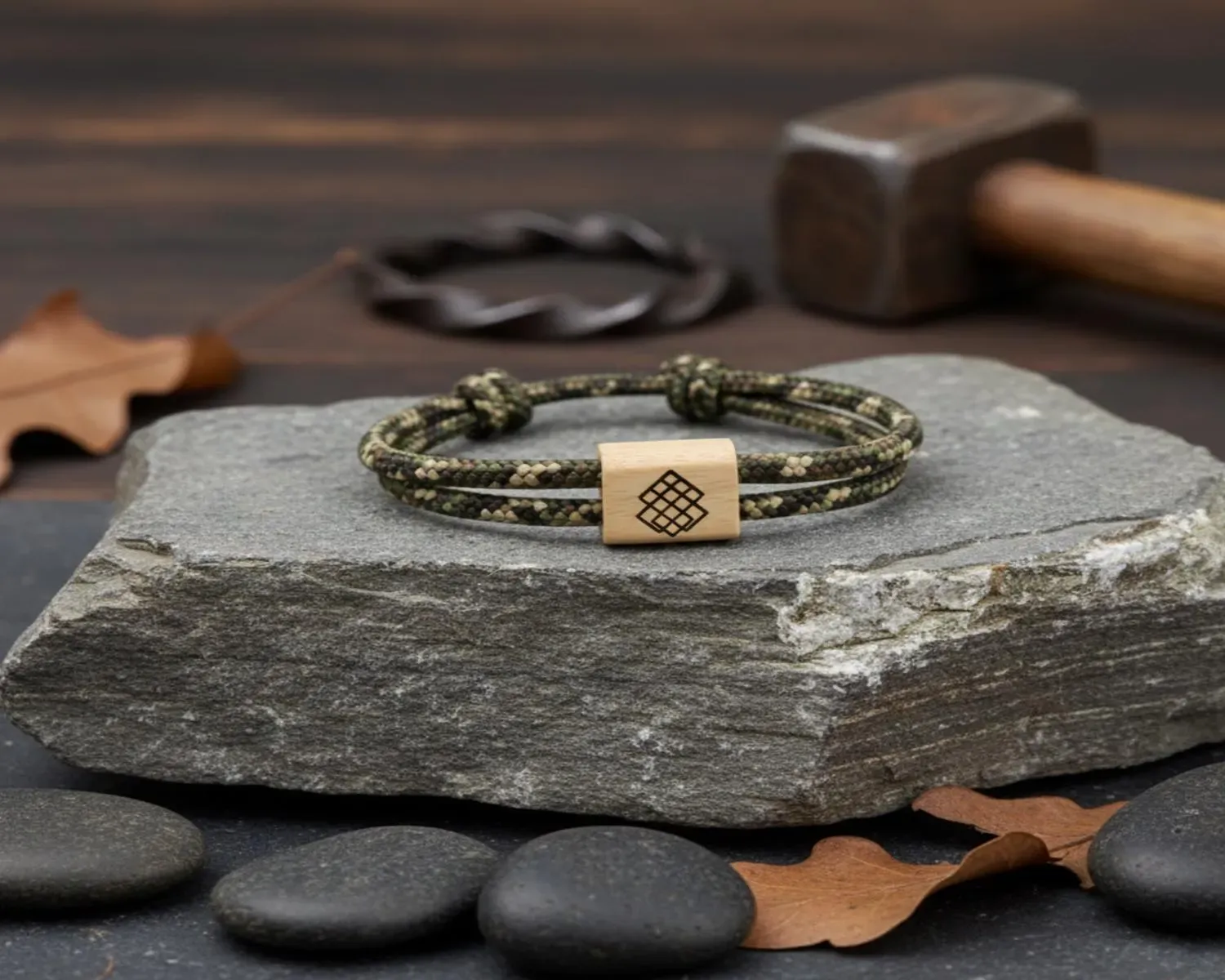 Bracelet vert kaki gravé du nœud nordique, posé près d'un maillet en bois
