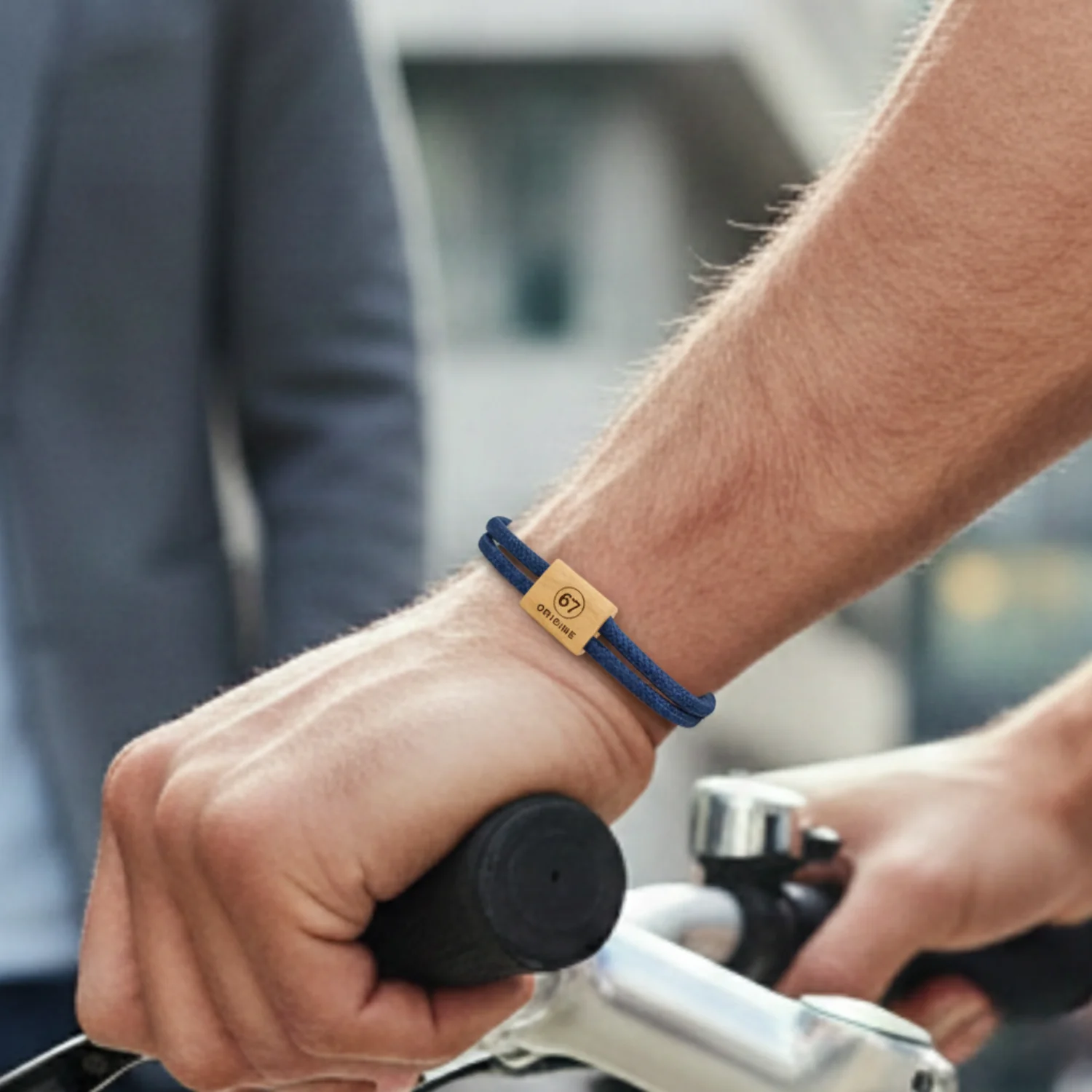 Bracelet bleu porté au poignet d'un cycliste, main sur le guidon