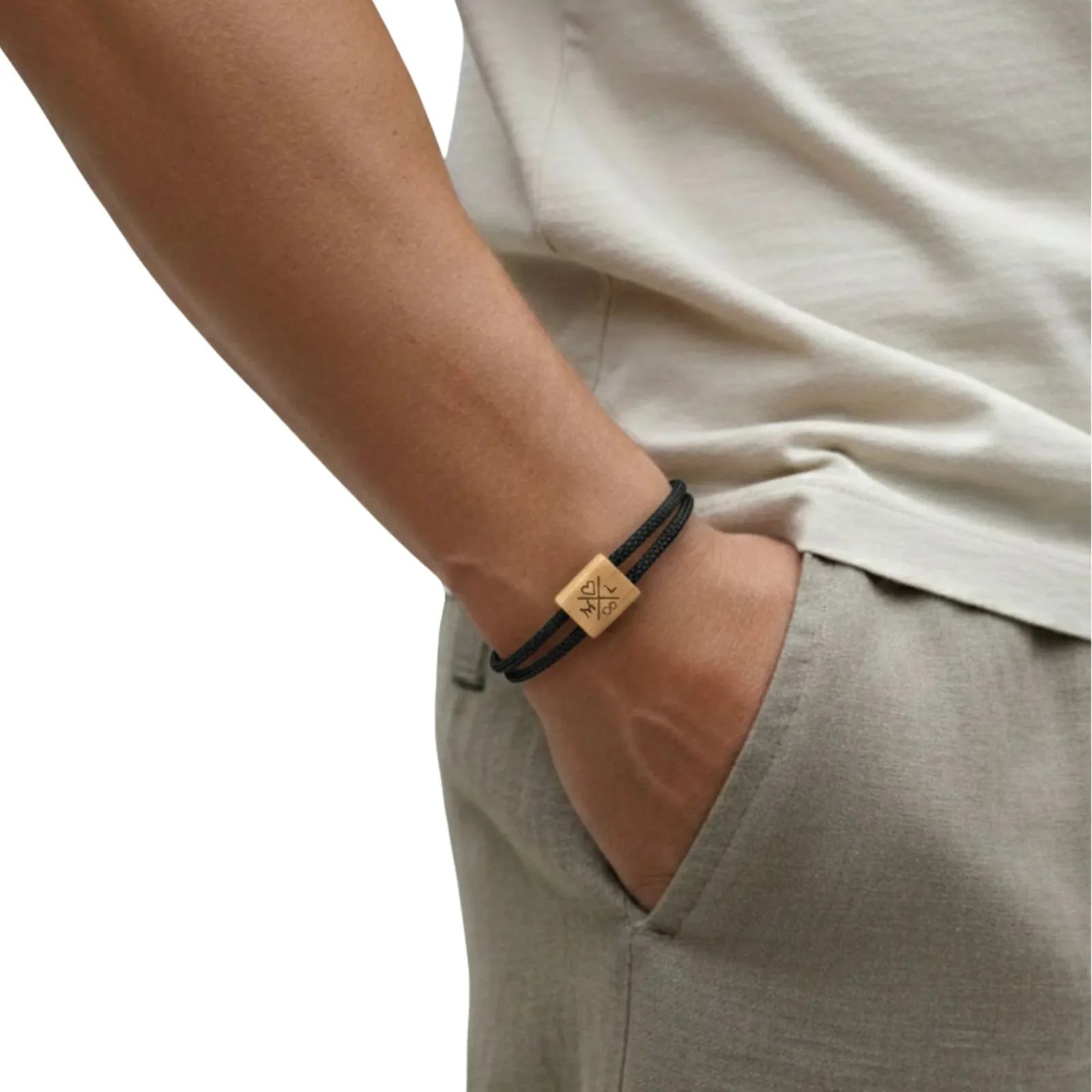 Bracelet noir porté au poignet, main dans la poche d'un pantalon clair