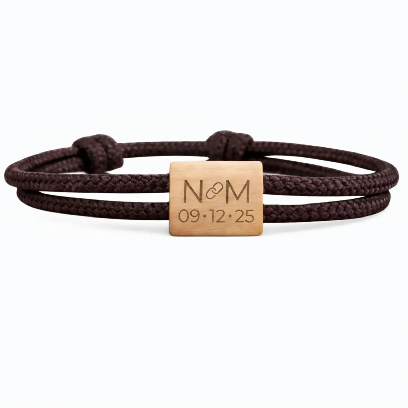 Initiales N et M séparées d'un maillon de chaîne, date 09 · 12 · 25, cordon marron foncé