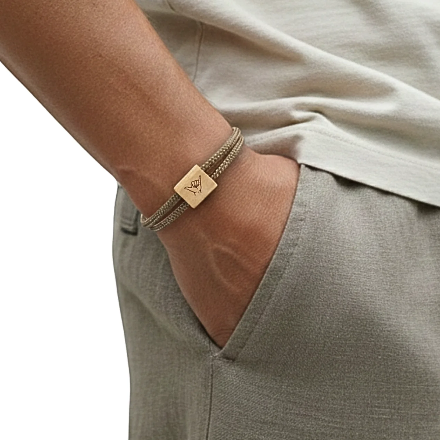Bracelet porté au poignet, main dans la poche d'un pantalon clair